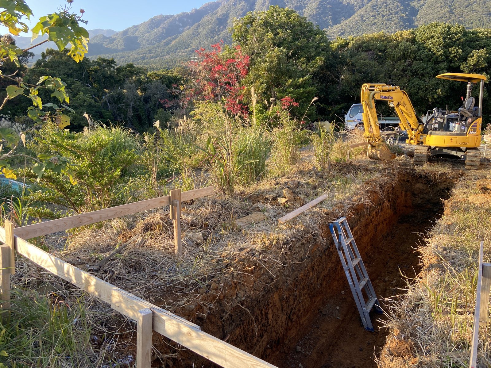 山と森を背にした敷地で、排水浄化システムのためのトレンチを掘削しているところ